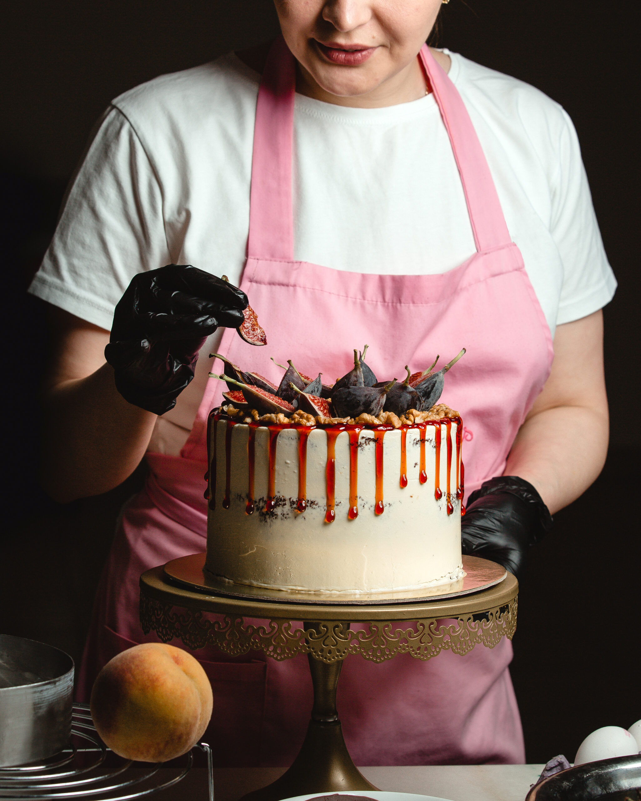 woman adding fig piece on classic cake decorated with figs and syrup